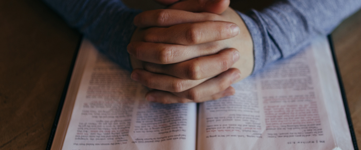 Praying hands with Bible