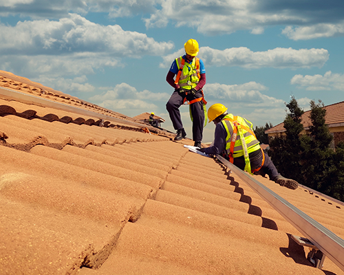 two men working on a roof, looking at a diagram.