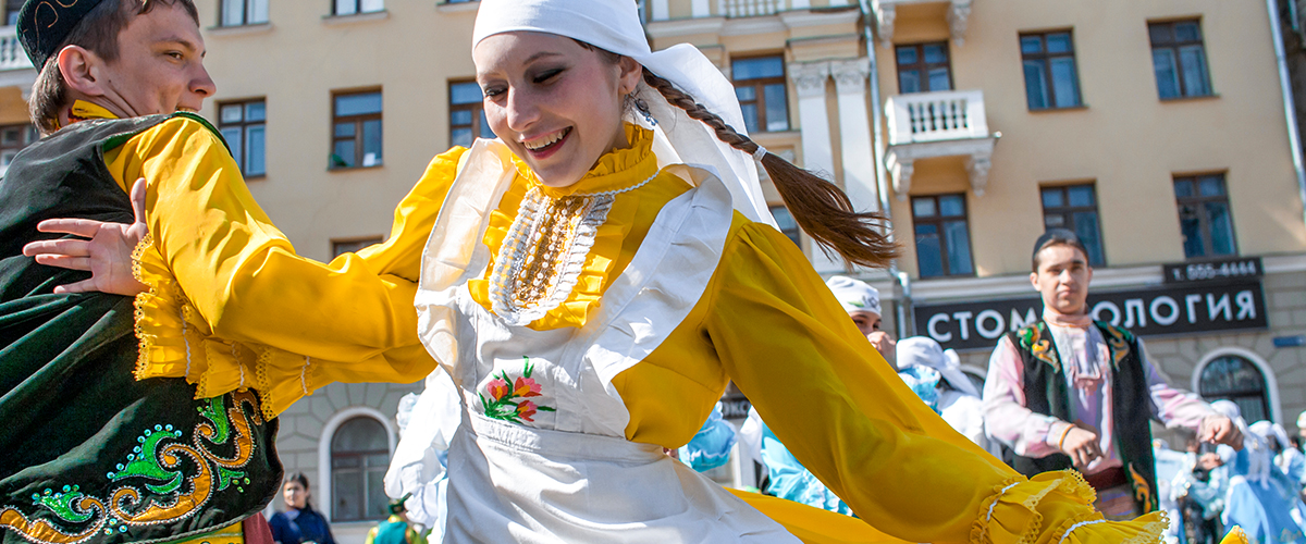A Tatar couple dances in traditional folk clothing.