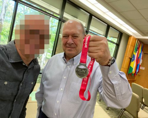 At a recent TWR staff meeting in North Carolina, John presented TWR President Lauren Libby with his “exclusive original” medal from completing the race on behalf of the TWR Dream Team. [ Image by TWR ]