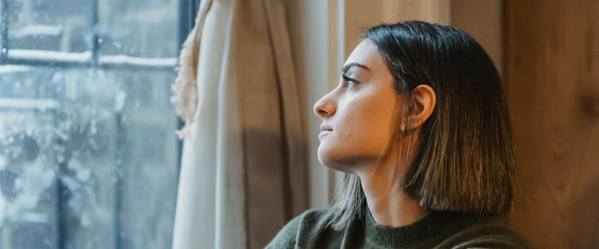 A woman looks out of the window into the rain
