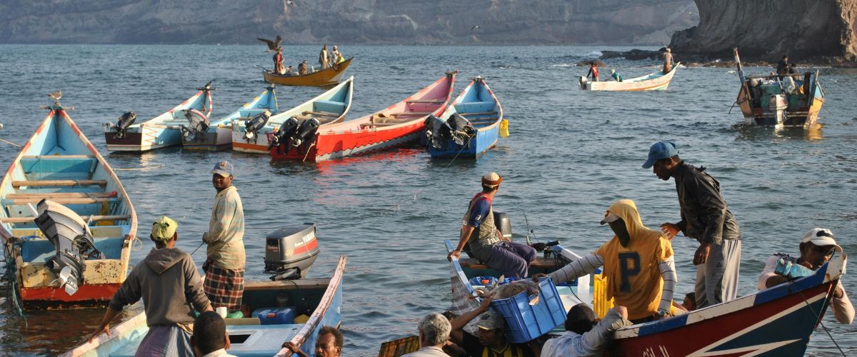 Men gather in colorful fishing boats in Yemen.